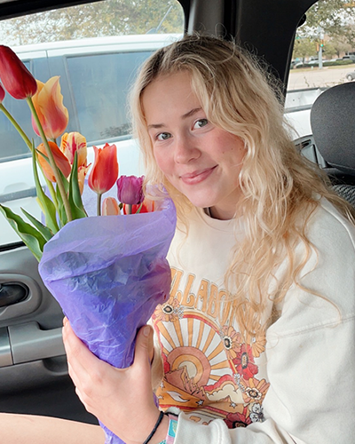 Caitlin in car, holding tulips.